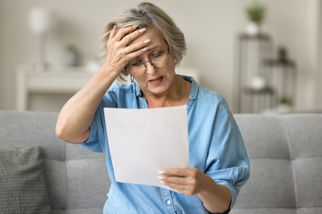 Stressed older woman looking at medical bill