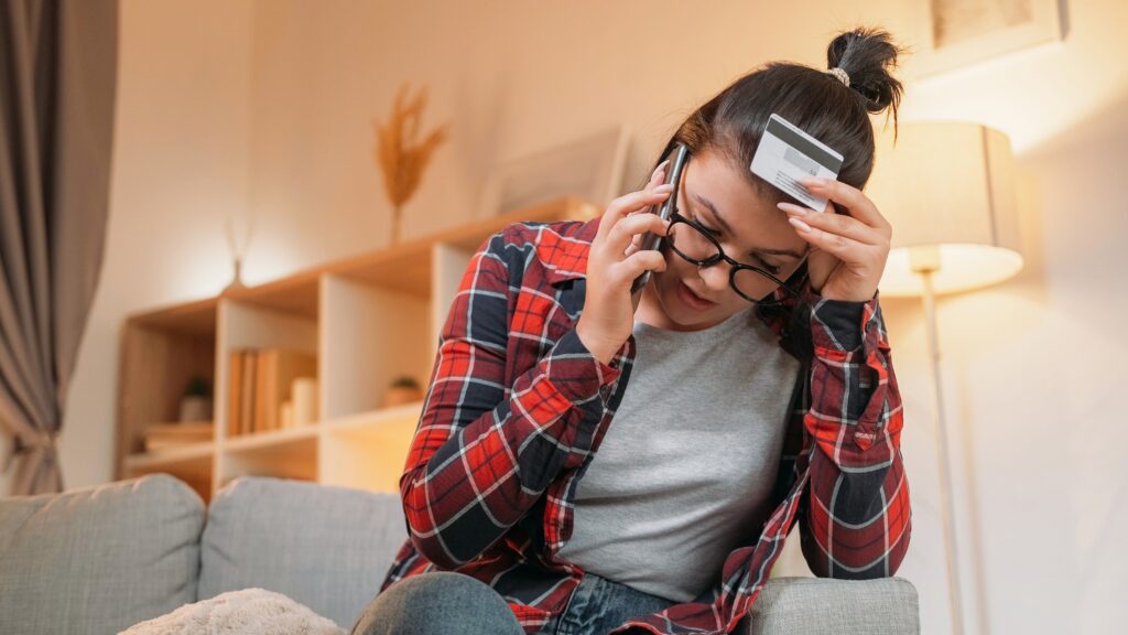Stressed woman talking on phone about credit card debt