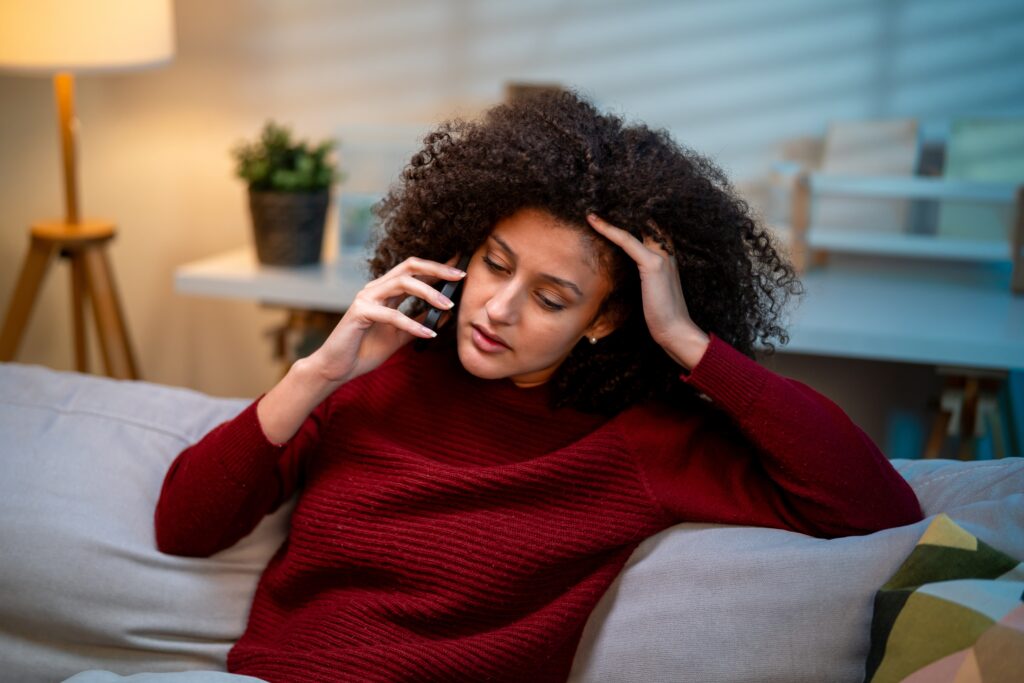 Stressed woman talking on phone in living room